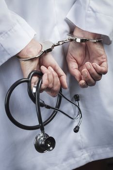 Female Doctor or Nurse In Handcuffs and Lab Coat Holding Stethoscope.