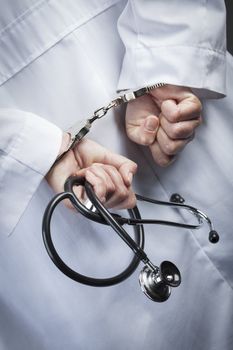 Female Doctor or Nurse In Handcuffs and Lab Coat Holding Stethoscope.