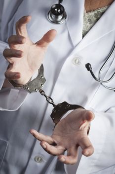 Female Doctor or Nurse In Handcuffs Wearing Lab Coat and Stethoscope.