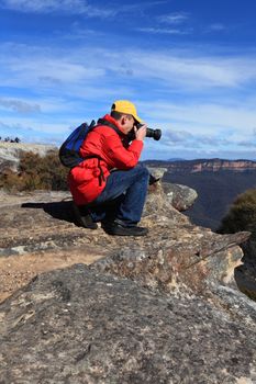 A photographer shoots photos of a scenic mountain landscape.