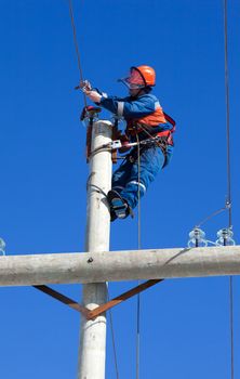 electrician working on top of an electricity pylon with the use of claws- manholes and  belt