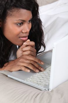 Black lady using laptop in bed