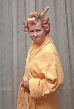 Young woman in a dressing gown raises a rolling pin.