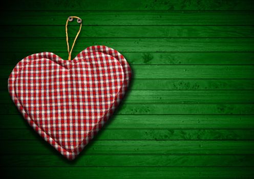 Handmade clothe heart hanging on green wooden background