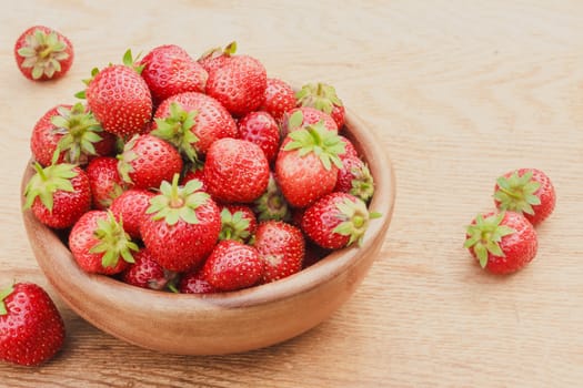 Old Wooden Bowl Filled With Succulent Juicy Fresh Ripe Red Strawberries On An Old Table top