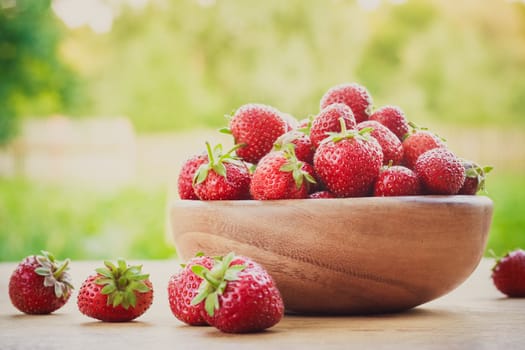 Old Wooden Bowl Filled With Succulent Juicy Fresh Ripe Red Strawberries On An Old Table top