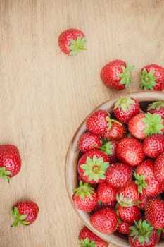 Old Wooden Bowl Filled With Succulent Juicy Fresh Ripe Red Strawberries On An Old Table top