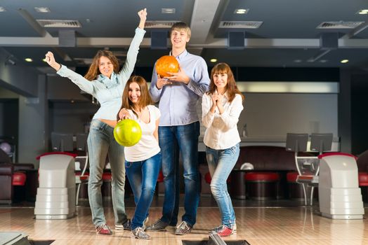 Group of young friends playing bowling, spending time with friends