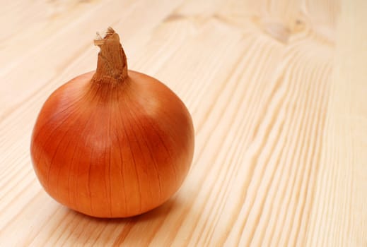 Whole white onion with skin, on a wooden table