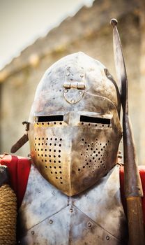 Medieval knight in helmet on ancient wall background