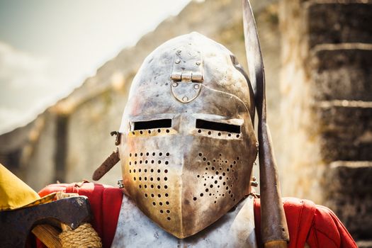 Medieval knight in helmet on ancient wall background