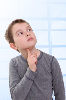 Eight Years old Kid looking up thinking, wondering about something, perhaps math problems