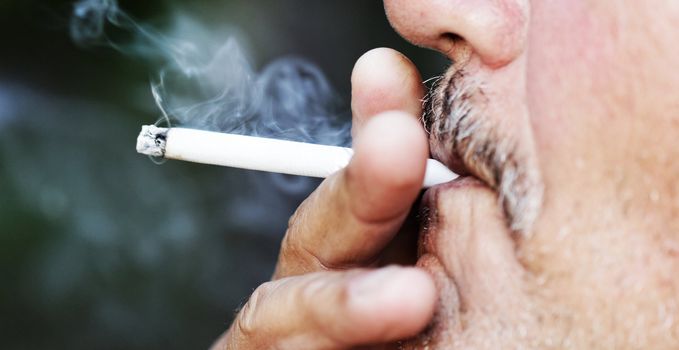 Smoking a cigarette against a dark background