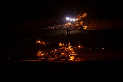 Coal mining in an open pit with huge industrial machine at night shoot