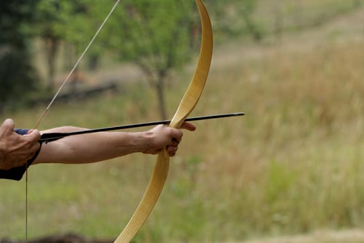 archery man shooting arrow with bow in the nature