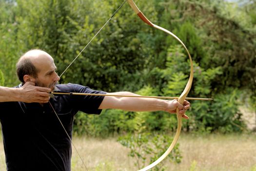 archery man shooting arrow with bow in the nature