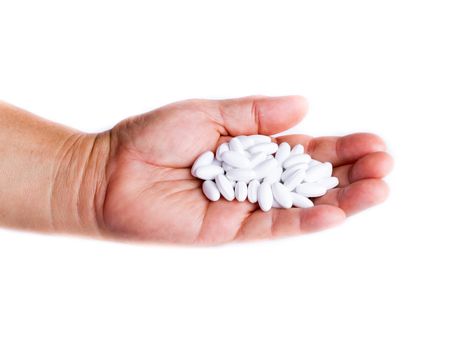 Adult holding a pile of white medicine pill in hand on white background