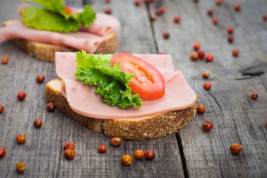 Delicious ham sandwiches on wooden textured background. 