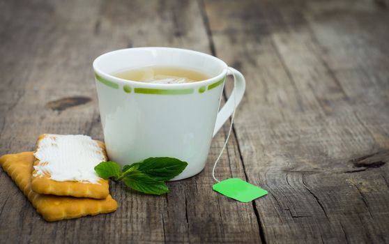 A cup of mint tea with cookies on wood background