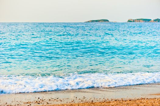 aqua turquoise sea rolls on the beach at dawn