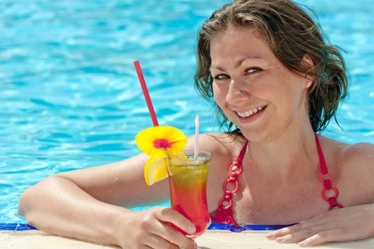 charming girl in the pool and a glass of alcoholic cocktail