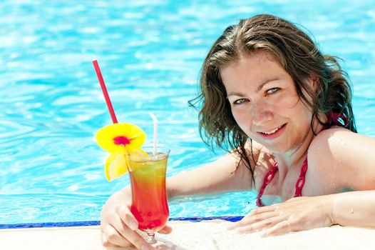 charming brunette in the pool holding a glass of alcoholic cocktail