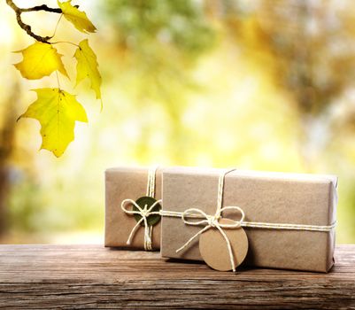 Handcrafted gift boxes on aged  wooden boards with an autumn foliage background