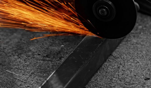 Metal sawing with hand grinder. Sparks while grinding iron.