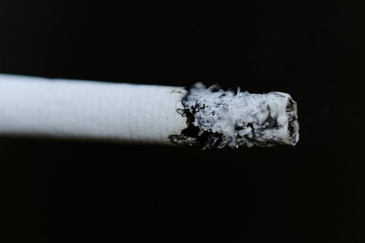 Smoking a cigarette against a dark background