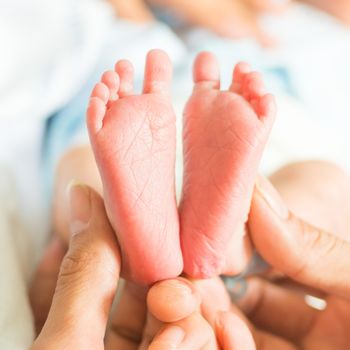 feet of baby holds on finger hands