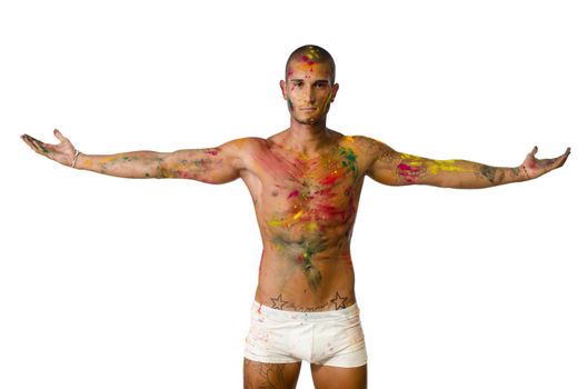 Attractive young man shirtless, skin painted all over with bright Honi colors with arms wide open