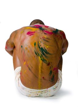 Muscular back of young man sitting on the floor with skin all painted with bright colors