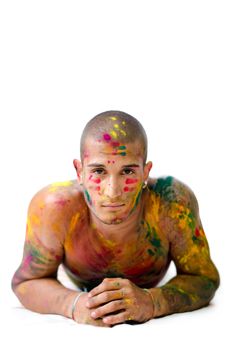 Attractive young man shirtless, skin painted all over with bright Honi colors on his elbows on the floor