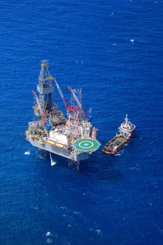 The offshore drilling oil rig and supply boat top view from aircraft.