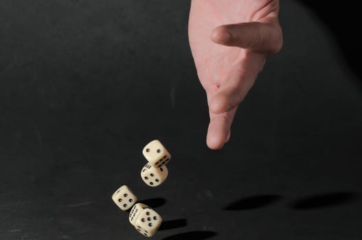 One Left Male Hand Playing Dice on a Black Background