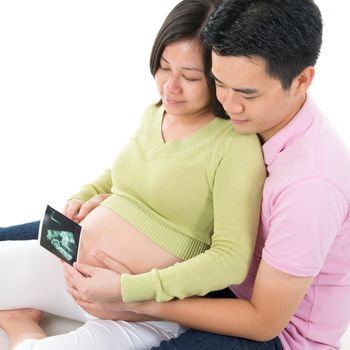 Asian Pregnant couple looking at ultrasound scan photo of unborn child