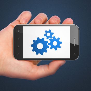 Web development concept: hand holding smartphone with Gears on display. Mobile smart phone in hand on Blue background, 3d render