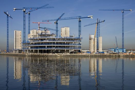 Construction cranes building a waterside office development
(In Salford Quays in Greater Manchester in Great Britain)