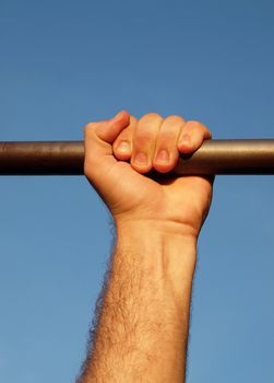 Hand on a crossbeam on a background of the blue sky    