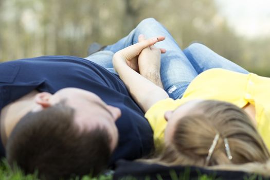 Top view of couple lying on the grass with heads together