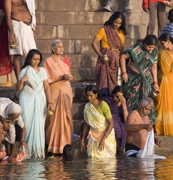 Group of pilgrims on the Hindu ghats on the banks of the Holy River Ganges (Ganga) in Varanasi (Benares) in the Uttar Pradesh region of northern India.