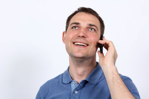 Smiling young man on his mobile phone against a white background