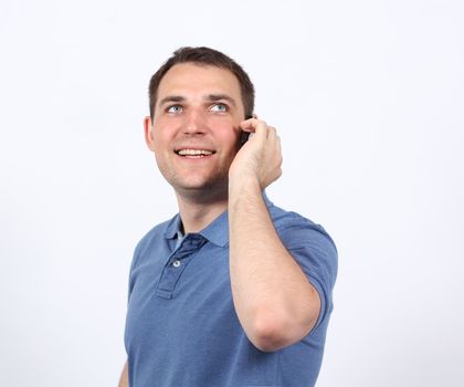 Smiling young man on his mobile phone against a white background