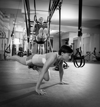 Crossfit fitness TRX training exercises at gym woman push-up and dip rings man workout