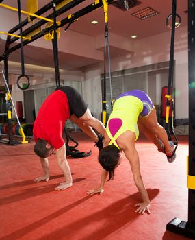 Crossfit fitness TRX training exercises at gym woman and man push-up pushup