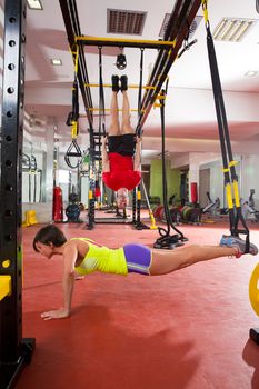 Crossfit fitness TRX training exercises at gym woman push-up and dip rings man workout