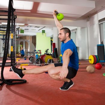 Crossfit fitness man balance Kettlebells with one leg exercise at gym workout