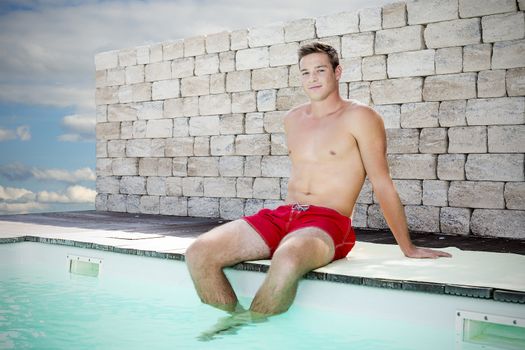 Young handsome man sitting on the edge of a swimming pool with shorts