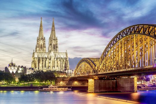 Illuminated Dom in Cologne with bridge and rhine at sunset