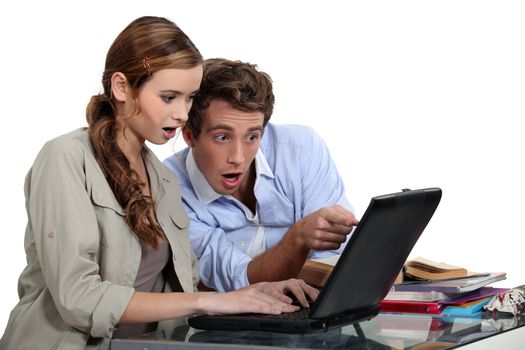 Shocked couple pointing at a laptop